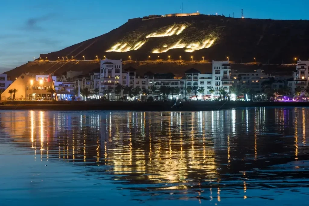 Agadir Bay by night with the illuminated mountain inscription reflecting on the ocean