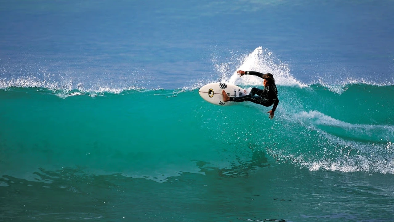 Surfer riding a powerful turquoise wave in Taghazout, Agadir